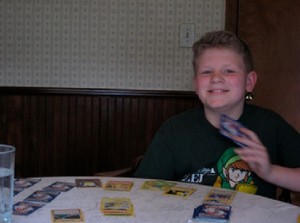 Foto de menino segurando cartas do Pokémon